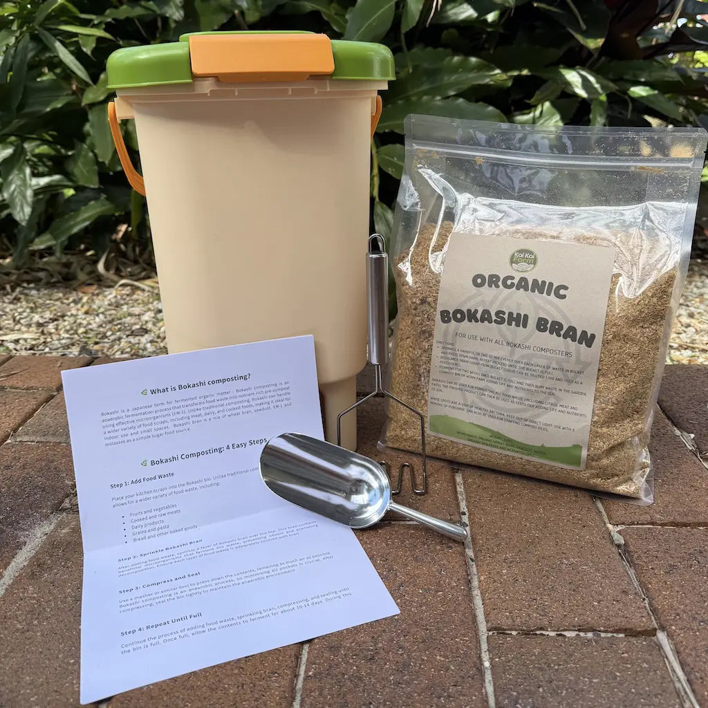 Composting kit with container, organic bokashi bran, instructions, and scoop on a stone surface.