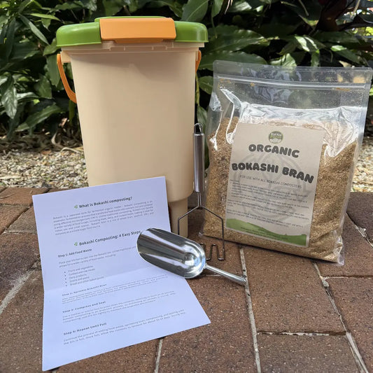Composting kit with container, organic bokashi bran, instructions, and scoop on a stone surface.
