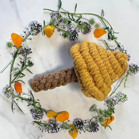 Rope toy with a yellow top and brown handle surrounded by flowers on a white background
