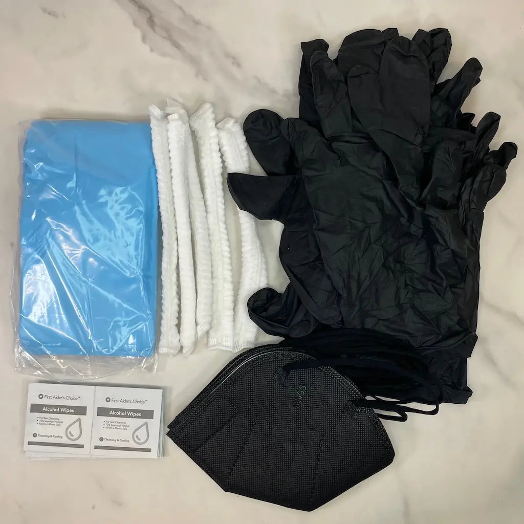 Set of mycology PPE gear laid out on a marble surface, including black nitrile gloves, a black KN95 mask, alcohol wipes, a blue plastic apron and white bouffant caps