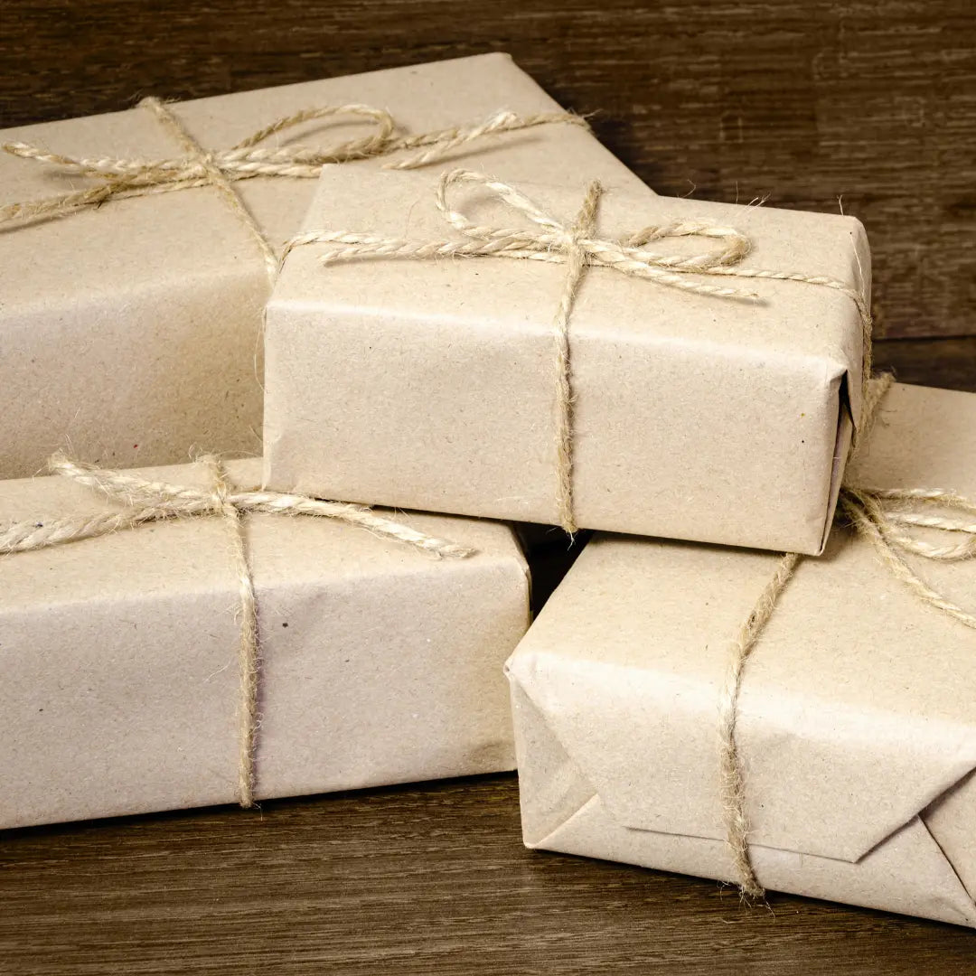 Stack of gift boxes wrapped in beige paper with string on a wooden surface
