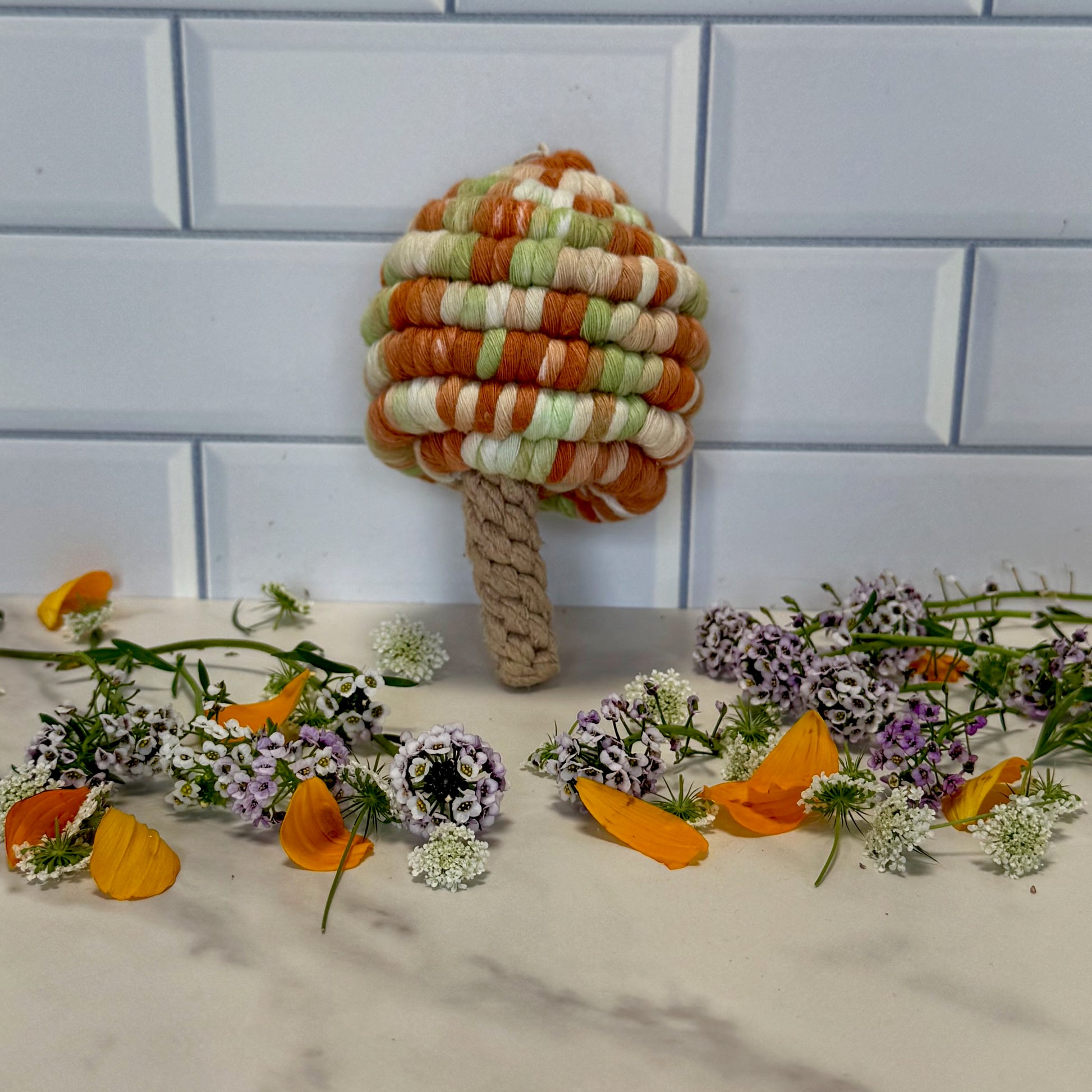 Colourful woven mushroom with flowers on a tiled wall background