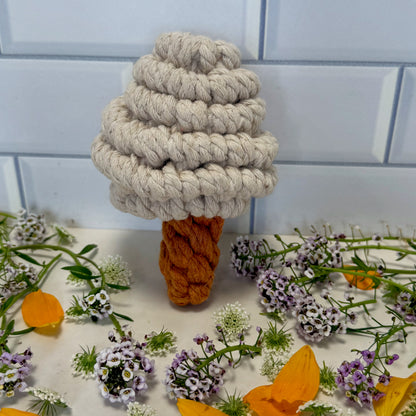 Textured mushroom-shaped object with a brown base on a white surface with flowers and greenery.