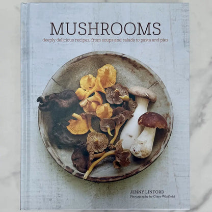 Cookbook cover featuring a plate of mushrooms with text about recipes on a light background