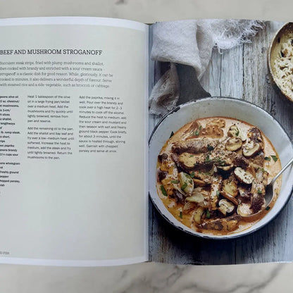 Open cookbook showing a recipe for Beef and Mushroom Stroganoff with a dish of the prepared meal.