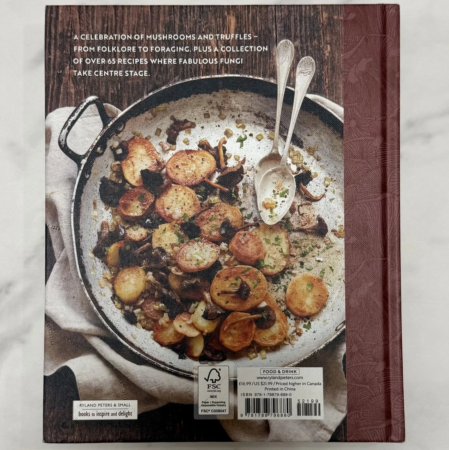 Cookbook cover with a dish of potatoes and mushrooms on a wooden surface