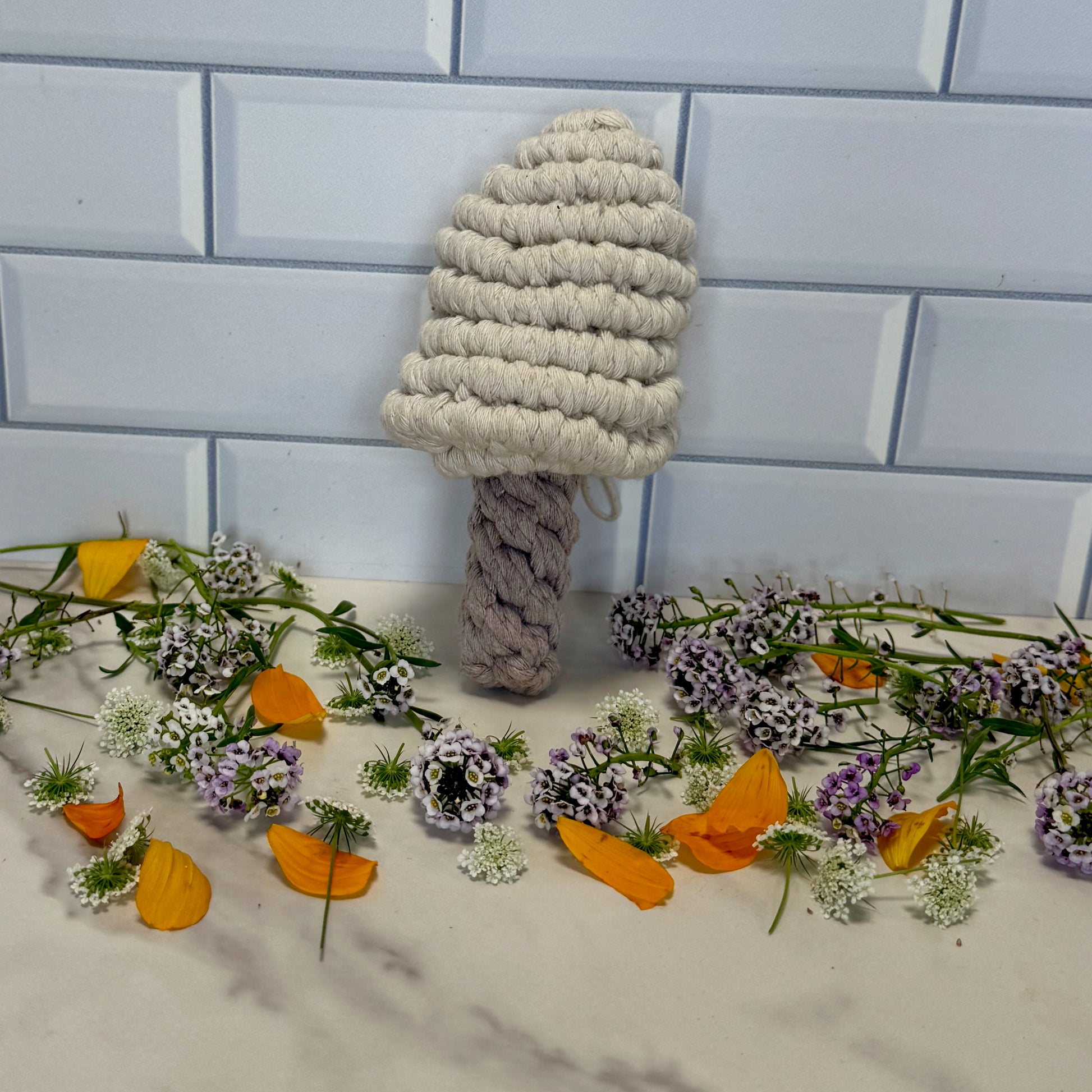 Textured mushroom-shaped object on a tiled floor with flowers and leaves.